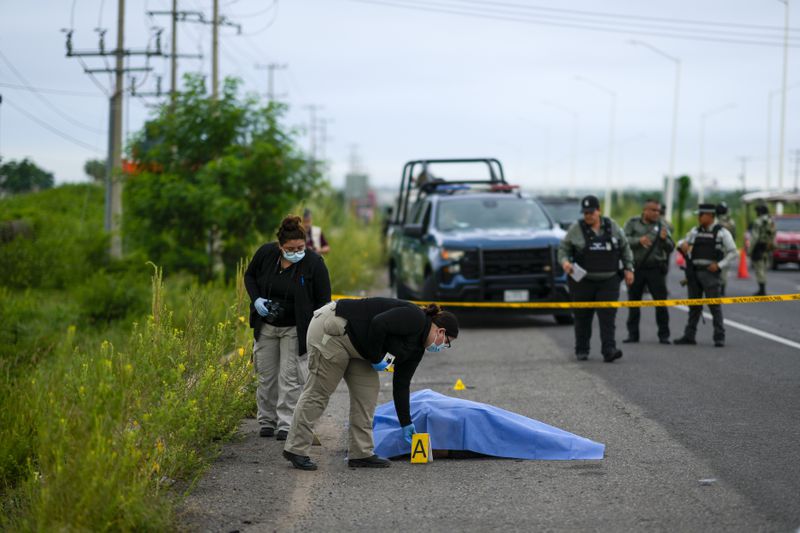 Crime scene investigators work at the site where a body was found lying on the side of a road in Culiacan, Sinaloa state, Mexico, Saturday, Sept. 21, 2024. (AP Photo/Eduardo Verdugo)