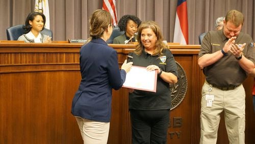 Cobb County Commissioner Keli Gambrill (left) presents a certificate of recognition to Cobb County 911 operator Dana Bell during a County Commission meeting Monday, March 21, 2022. Bell was recognized for answering more than 20,000 calls in less than a year, breaking the county's record for most calls handled.