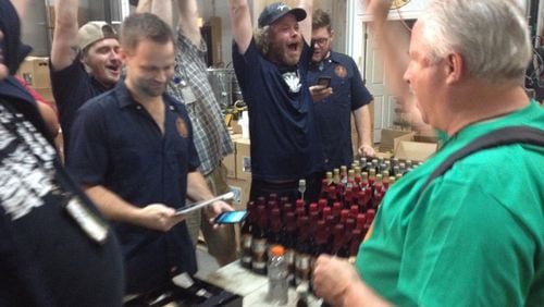 Brad Durham pays for a tour and gets three bottles of souvenir beer at Burnt Hickory Brewery in Kennesaw just after the stroke of midnight on July1. (Holly Steel /hsteel@ajc.com)