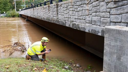 A GDOT bridge inspector checks for damage where Northside Drive NW crosses Peachtree Creek in Atlanta on Friday, Sept. 27, 2024 following a night of heavy rain from Hurricane Helene.   Ben Gray for the Atlanta Journal-Constitution