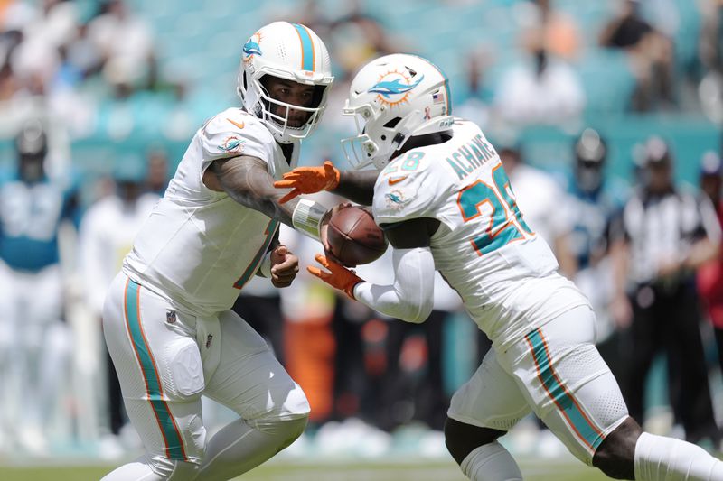 Miami Dolphins quarterback Tua Tagovailoa (1) hands the ball to running back De'Von Achane (28) during the first half of an NFL football game against the Jacksonville Jaguars, Sunday, Sept. 8, 2024, in Miami Gardens, Fla. (AP Photo/Rebecca Blackwell)