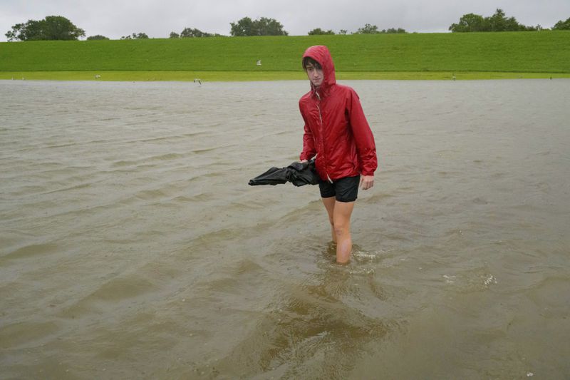 FILE - Cameron Henry looks at the water build up from Hurricane Francine in front of the levee protection, background, along Lakeshore Drive along Lake Ponchartrain in New Orleans, Sept. 11, 2024. (AP Photo/Matthew Hinton, File)