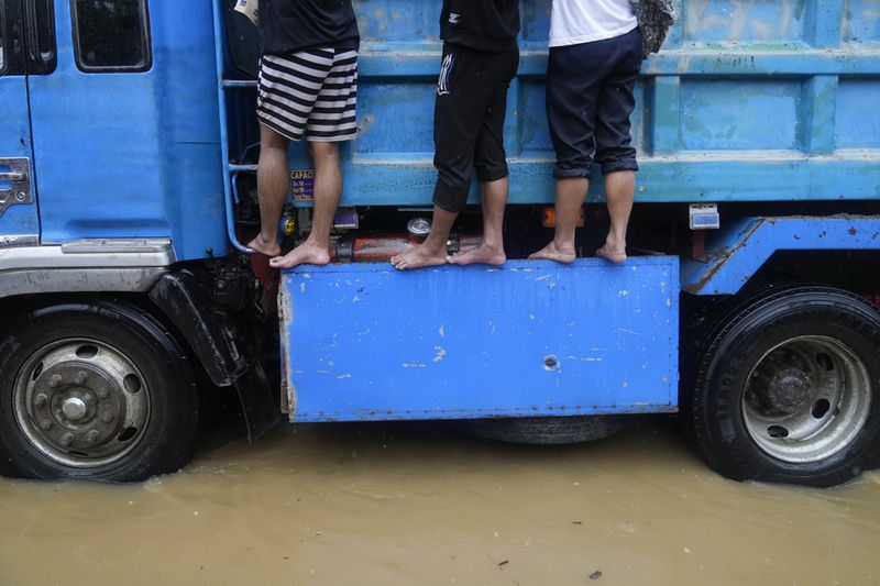 Residents ride a truck as they negotiate a flooded street caused by heavy rains from Tropical Storm Yagi, locally called Enteng, in Cainta, Rizal province, Philippines, Monday, Sept. 2, 2024. (AP Photo/Aaron Favila)