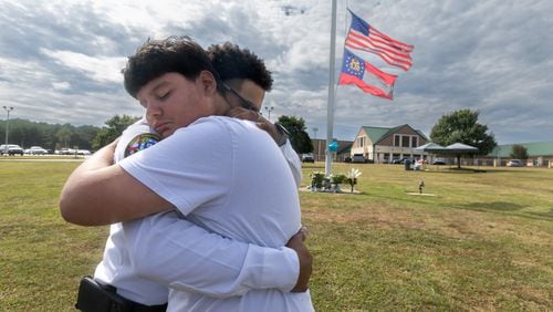 9th grade student, Jose Ortiz-14 (left) is hugged by Georgia State chaplain, Ronald Clark as students and well wishers arrived with flowers to place at the flag pole at Apalachee High School in Winder on Thursday, Sept. 5, 2024. A 14-year-old is accused of shooting and killing two fellow students and two teachers and injuring nine others at Apalachee High School on Wednesday. (John Spink/AJC)