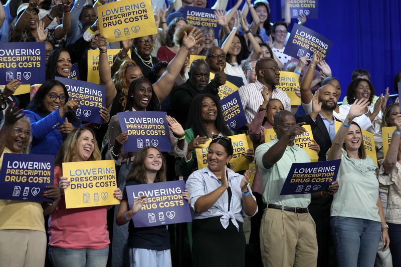 Attendees listen as President Joe Biden and Democratic presidential nominee Vice President Kamala Harris speak about the administration's efforts to lower prescription drug costs during an event at Prince George's Community College in Largo, Md., Thursday, Aug. 15, 2024. (AP Photo/Susan Walsh)