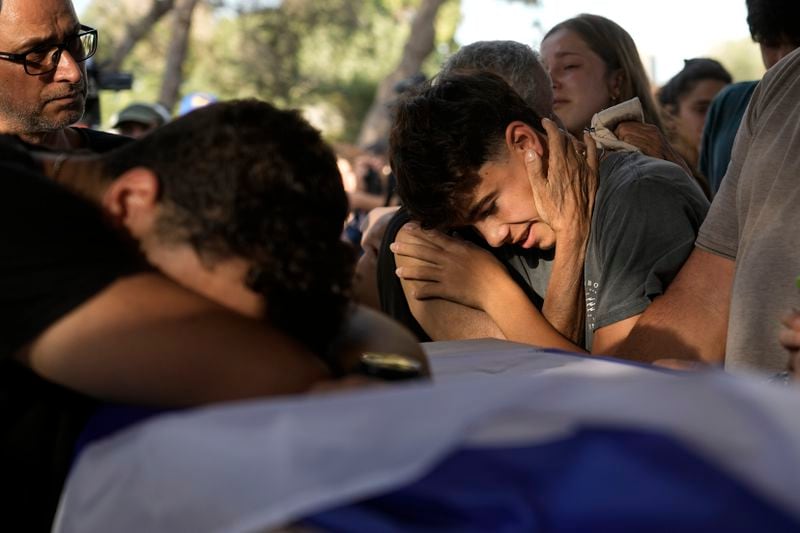 Family members mourn over the coffin of Yoram Metzger during his funeral at a cemetery of the kibbutz Nir Oz, southern Israel, Thursday, Aug. 22, 2024. Metzger's body was one the six bodies of hostages, taken in Hamas' Oct. 7 attack, recovered by Israel's military during an operation in the Gaza Strip. (AP Photo/Tsafrir Abayov)