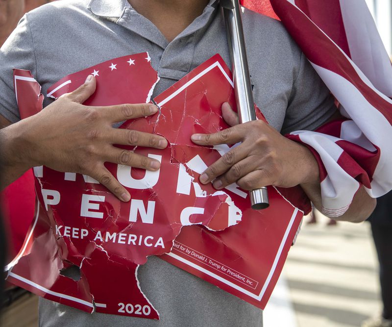 11/05/2020 —  Atlanta, Georgia — A President Donald Trump supporter holds onto a sign that was ripped during a rally outside of State Farm Arena in downtown Atlanta, Thursday, November 5, 2020. Inside State Farm Arena, workers were busy finishing up the process of counting ballots from Fulton County voters. (Alyssa Pointer / Alyssa.Pointer@ajc.com)