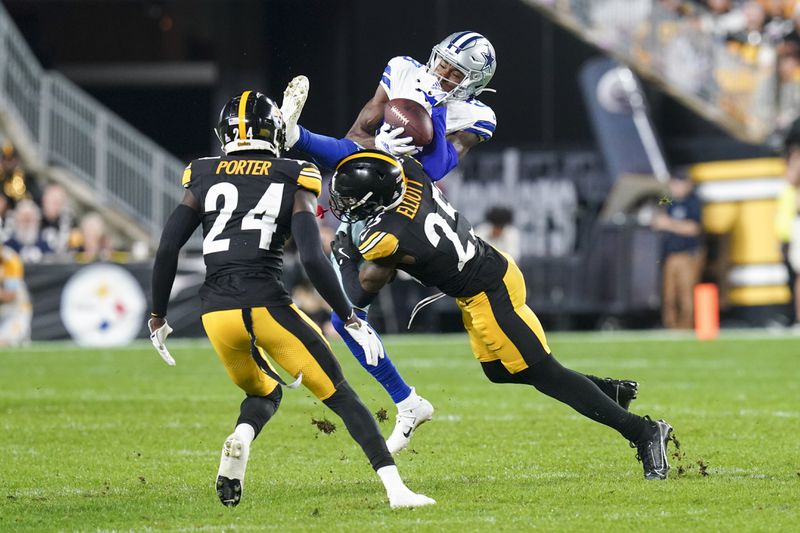 Dallas Cowboys wide receiver Jalen Brooks, top, catches a pass while being hit by Pittsburgh Steelers safety DeShon Elliott (25) during the first half of an NFL football game, Sunday, Oct. 6, 2024, in Pittsburgh. Steelers' Joey Porter Jr. (24) looks on. (AP Photo/Matt Freed)