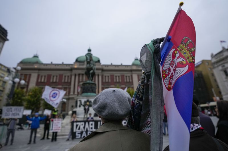 A woman holds a Serbian flag during a pro-Palestinian gathering in Belgrade, Serbia, Saturday, Oct. 5, 2024. (AP Photo/Darko Vojinovic)