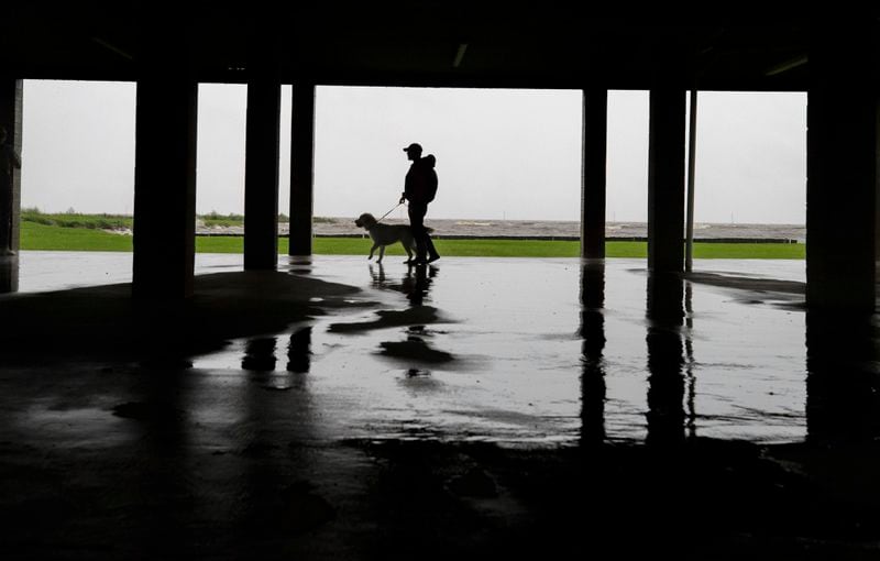 Seth Tartaglia and his dog Magnolia Jane check out the waves and winds in Frenier Landing, La., ahead of Hurricane Francine, Wednesday, Sept. 11, 2024. (David Grunfeld/The Times-Picayune/The New Orleans Advocate via AP)