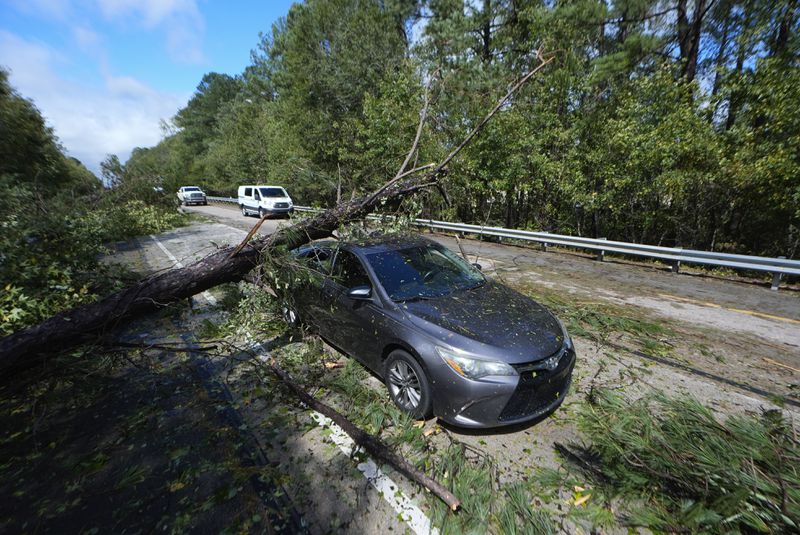 A tree rests on an adandoned car on Interstate 20 in the aftermath of Hurrican Helene Friday, Sept. 27, 2024, Grovetown, Ga. (AP Photo/John Bazemore)