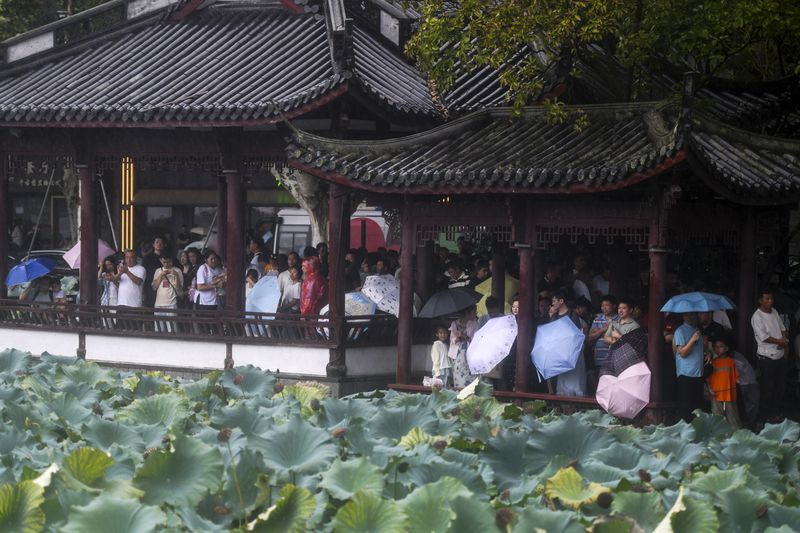 Tourists take shelter in pavilions from the rains brought by Typhoon Bebinca during the Mid-Autumn Festival holiday, in Hangzhou in east China's Zhejiang province, Monday, Sept. 16, 2024. (Chinatopix Via AP)