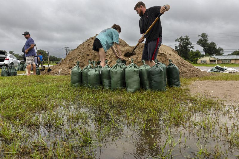 Rainwater accumulates around Nolan and Macie Melancon as they fill up sandbags for their home located a few miles away in Houma, La., as the region gets ready for the arrival of Hurricane Francine on Tuesday, Sept. 10, 2024. (Chris Granger /The Times-Picayune/The New Orleans Advocate via AP)