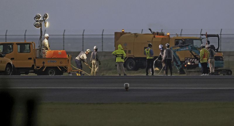 Workers are seen around a damaged taxiway at Miyazaki Airport in southwestern Japan, Wednesday, Oct. 2, 2024, after an explosion was reported. (Kyodo News via AP)