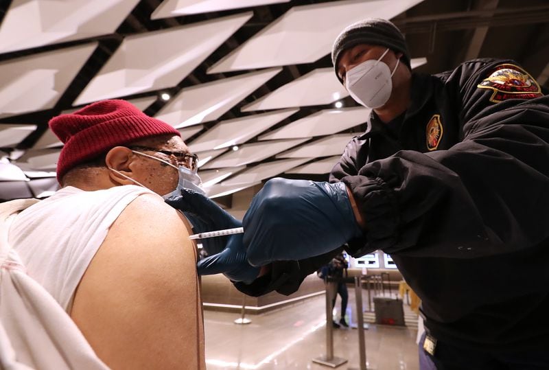 Philip McCollum gets a Pfizer vaccine from Atlanta Fire and Rescue Lt. Jathan Dortch at the Mercedes-Benz Stadium.  Curtis Compton / Curtis.Compton@ajc.com”