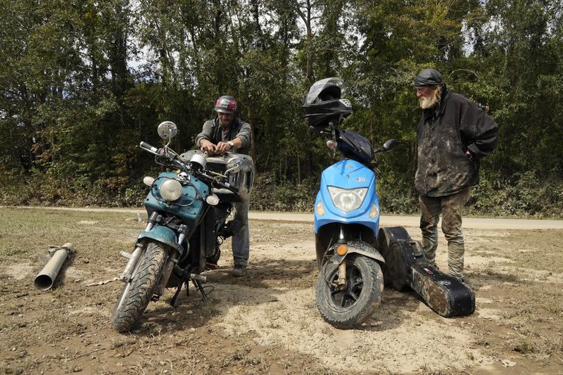 Friends Robert Smith and David Mayben salvage items from the home of a family member who passed away in flooding, Tuesday, Oct. 1, 2024 in Hendersonville, N.C., in the aftermath of Hurricane Helene. (AP Photo/Brittany Peterson)