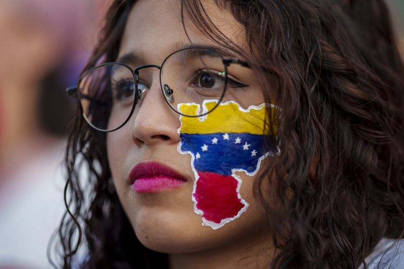 A woman with her face painted with the colors of Venezuela's national flag attends a protest against the official results that declared President Nicolas Maduro the winner of the July presidential election in Madrid, Spain, Saturday, Aug. 17, 2024. (AP Photo/Manu Fernandez)