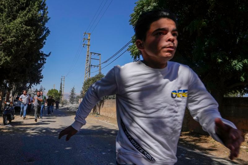 Journalists and resident run for cover following an Israeli airstrike in Baalbek, east Lebanon, Sunday, Oct. 6, 2024. (AP Photo/Hassan Ammar)