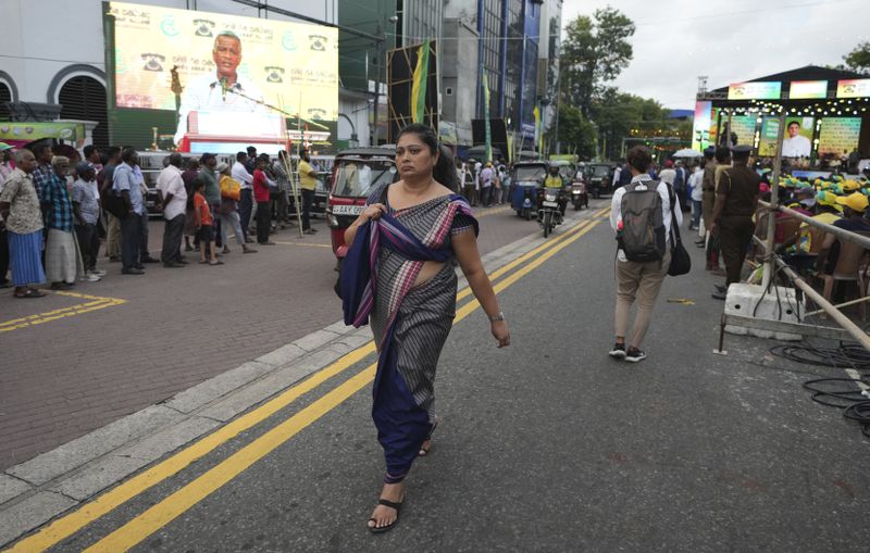 A woman walks on a street across which a large billboard showing a portrait of Sajith Premadasa, the presidential candidate and opposition leader of the Samagi Jana Balawgaya or United People's Power party, is displayed, in Colombo, Sri Lanka, Wednesday, Sept. 18, 2024. (AP Photo/Rajesh Kumar Singh)