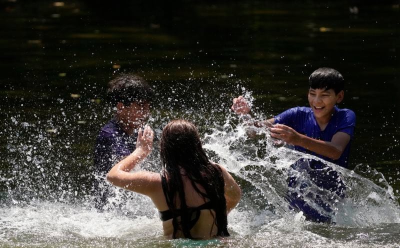 Leeann Gutierrez, center, splashes siblings Bo'Luke, left, and, Romeo, right, as they keep cool in the Guadalupe River, Wednesday, Aug. 21, 2024, in New Braunfels, Texas. (AP Photo/Eric Gay)