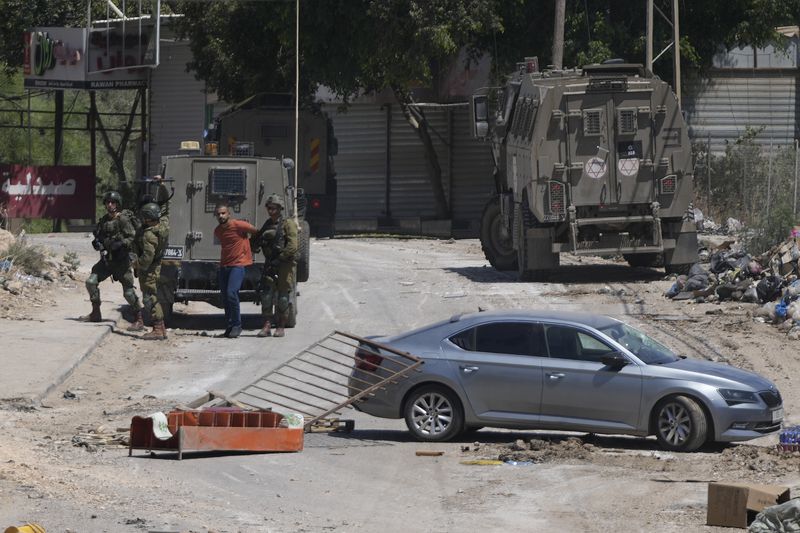 A Palestinian man is detained by members of the Israeli forces during a military operation in the West Bank refugee camp of Al-Faraa, Wednesday, Aug. 28, 2024. (AP Photo/Nasser Nasser)