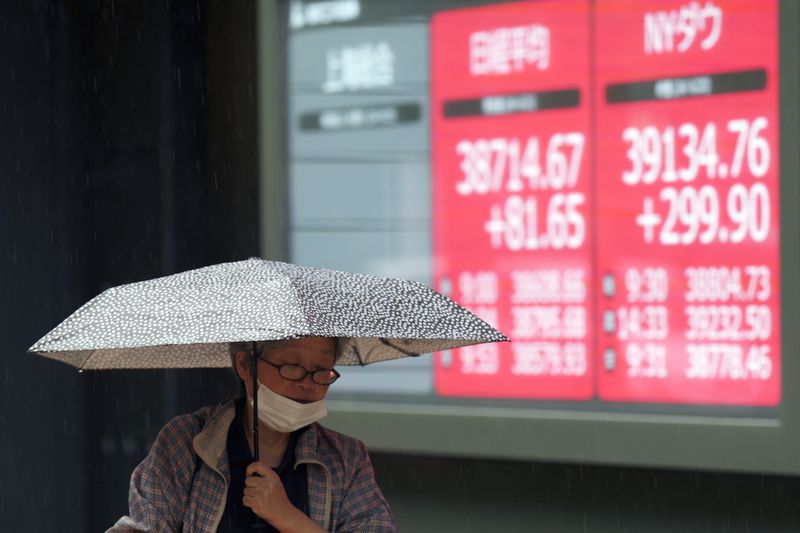 A person walks in front of an electronic stock board showing Japan's Nikkei and New York Dow indexes at a securities firm Friday, June 21, 2024, in Tokyo. (AP Photo/Eugene Hoshiko)