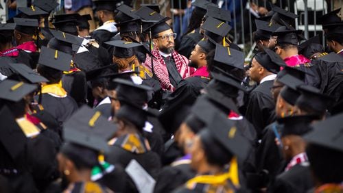 A Morehouse College graduate wears a keffiyeh and faces away from President Joe Biden to protest the war in Gaza during last month's commencement ceremony at the school in Atlanta. (Arvin Temkar / AJC)