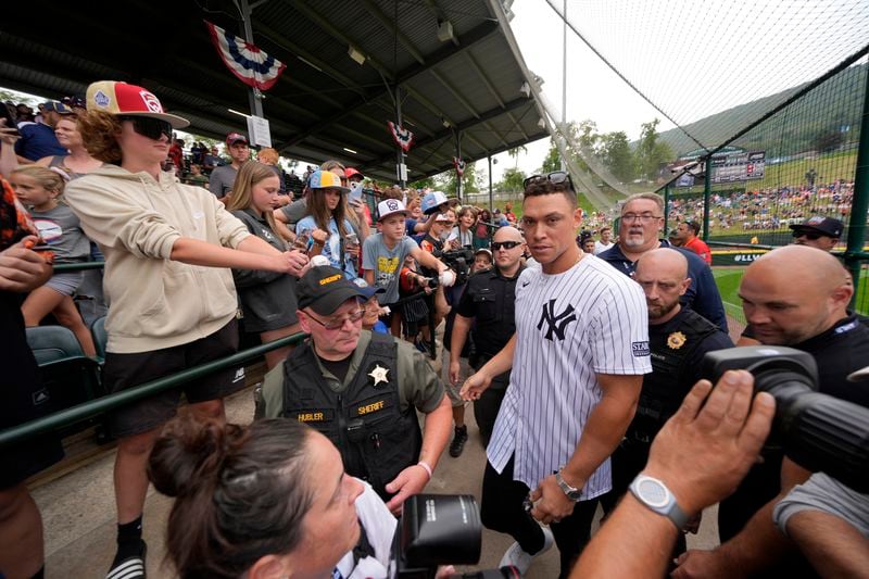 New York Yankees' Aaron Judge, center, makes his way to his seat at Lamade Stadium during a team visit to the Little League World Series tournament in South Williamsport, Pa., Sunday, Aug. 18, 2024. The Yankees will be playing the Detroit Tigers in the Little League Classic at Bowman Stadium in Williamsport, Pa., on Sunday Night Baseball. (AP Photo/Gene J. Puskar)