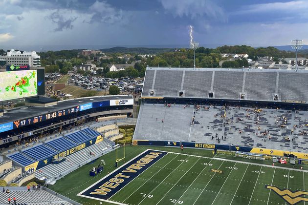 A lightning strike is shown in the distance above Mountaineer Field during an NCAA college football game between Kansas and West Virginia in Morgantown, W.Va., Saturday, Sept. 21, 2024. (AP Photo/John Raby)