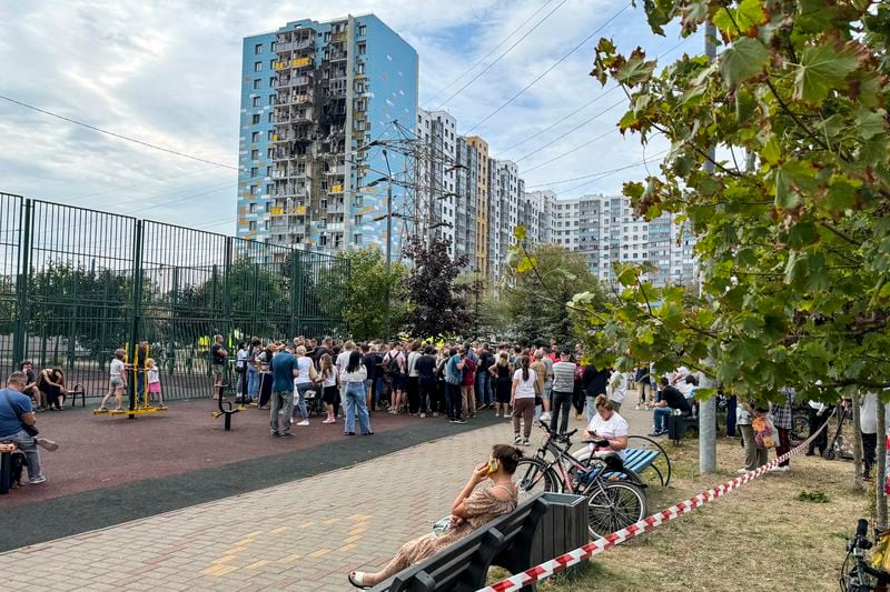 People gather to talk with local officials at the site of the damaged multi-storey residential building, following an alleged Ukrainian drone attack in Ramenskoye, outside Moscow, Moscow region, Russia, on Tuesday, Sept. 10, 2024. (AP Photo)