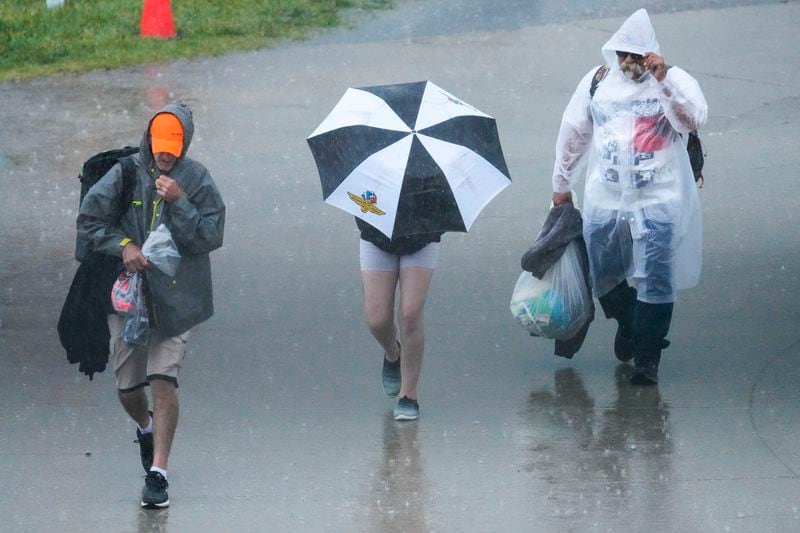 Fans walk in the rain during a thunderstorm delay before the start of the Indianapolis 500 auto race at Indianapolis Motor Speedway in Indianapolis, Sunday, May 26, 2024. (AP Photo/AJ Mast)