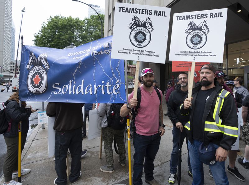 Rail workers picket in front of CN headquarters on the first day of a nationwide rail shutdown, after workers were locked out by CN and CPKC when new contract agreements weren't reached by the midnight deadline, in Montreal, Thursday, Aug. 22, 2024. (Ryan Remiorz/The Canadian Press via AP)