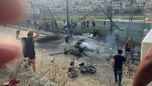 Residents rush to help injured children moments after a rocket attack hit a soccer field in the Druze town of Majdal Shams in the Israeli-controlled Golan Heights, Saturday, July 27, 2024. (AP Photo/Hassan Shams)