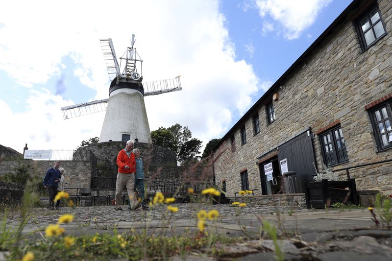 People walk from Falwell windmill and mill which is a temporary polling station, after casting their vote in Sunderland, England, Thursday, July 4, 2024.Britain goes to the polls Thursday after Prime Minister Rishi Sunak called a general election. (AP Photo/Scott Heppell)