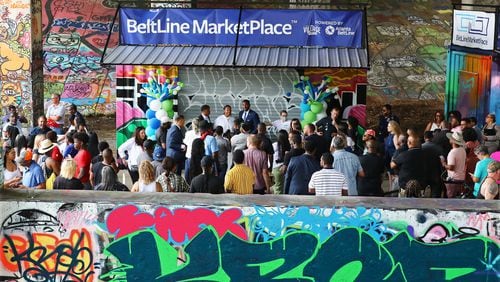 A crowd including Atlanta Mayor Andre Dickens, Atlanta Beltline President and CEO Clyde Higgs and The Village Market's Founder & CEO Dr. Lakeysha Hallmon (at center) gather for a ribbon-cutting ceremony for the inaugural Beltline Marketplace under the Freedom Parkway Bridge, on Wednesday, July 13, 2022. (Curtis Compton / Curtis Compton@ajc.com)