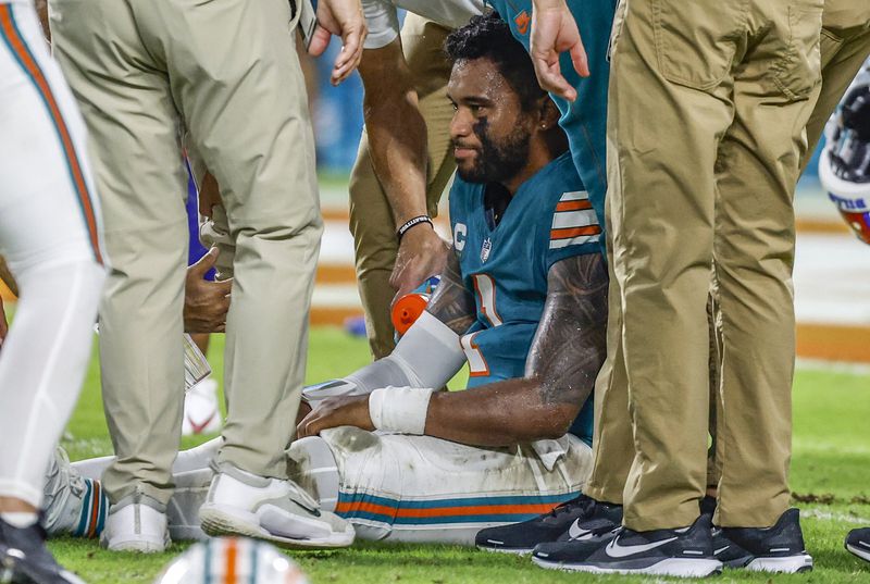 Miami Dolphins quarterback Tua Tagovailoa (1) sits on the field as he is attended to after an injury during the game against the Buffalo Bills in the second half of an NFL football game on Thursday, Sept. 12, 2024. (Al Diaz/Miami Herald via AP)