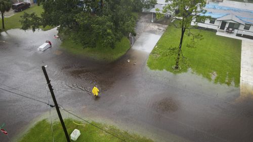 A pedestrian wades across a flooded street as a result of Tropical Storm Debby in the Shore Acres area of St. Petersburg, Fla., on Sunday, Aug. 4, 2024. (Max Chesnes/Tampa Bay Times via AP)