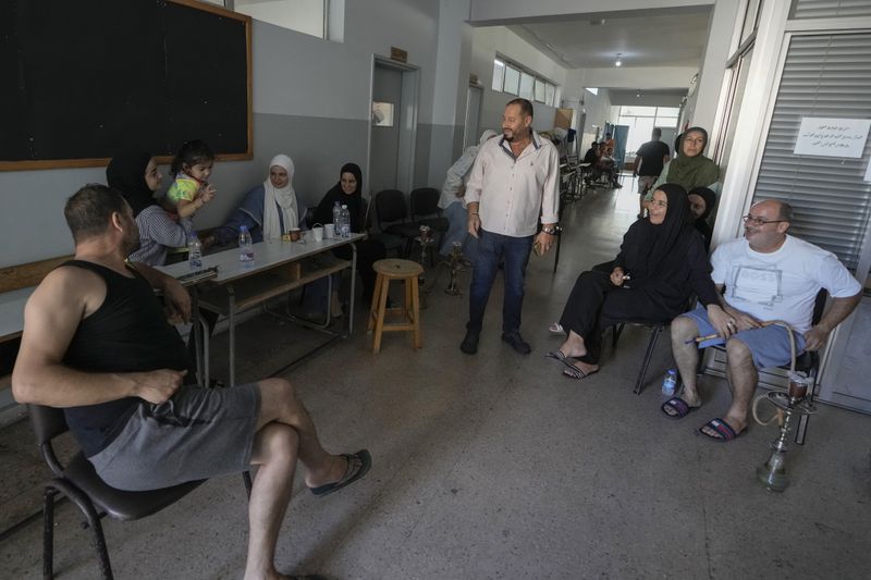 Displaced people gather in the hallway of a school in Beirut, after fleeing the Israeli airstrikes in the south, Thursday, Sept. 26, 2024. (AP Photo/Bilal Hussein)