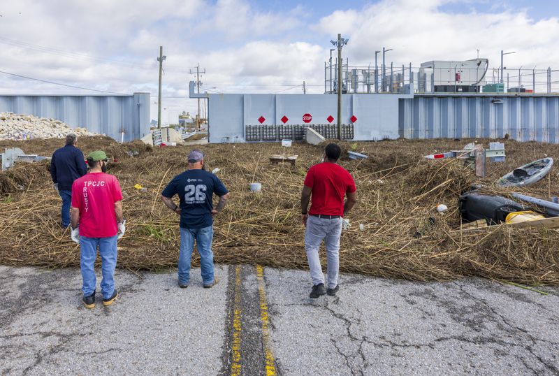 Cleaning crews view the pile of detritus and marsh grass that piled up against a flood wall from Hurricane Francine in Terrebonne Parish, La., Thursday, Sept. 12, 2024. (Chris Granger/The Times-Picayune/The New Orleans Advocate via AP)