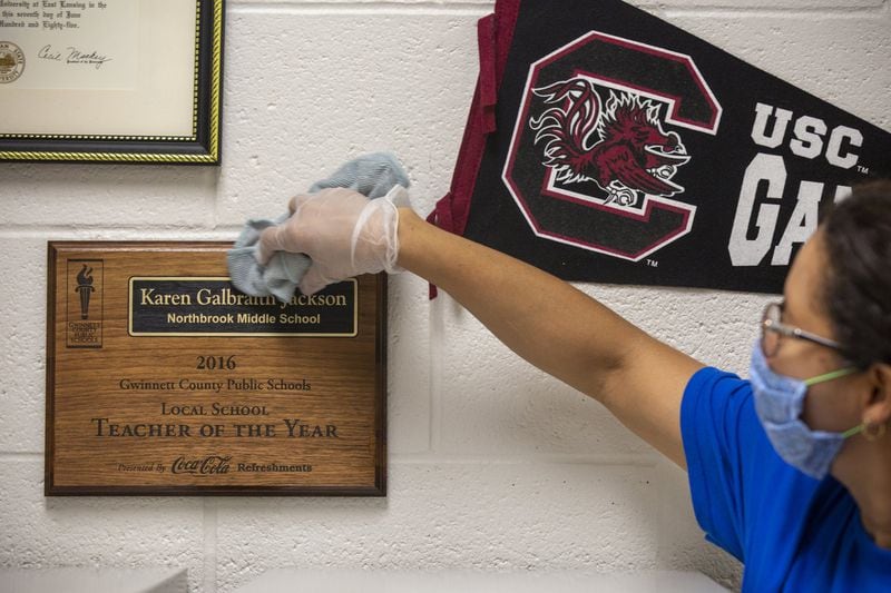 Brenda Oquendo, a custodian at Northbrook Middle School in Suwanee, Georgia, disinfects a plaque on Wednesday, July 8, 2020. Gwinnett County Schools plans to reopen for in-person instruction on August 12. 