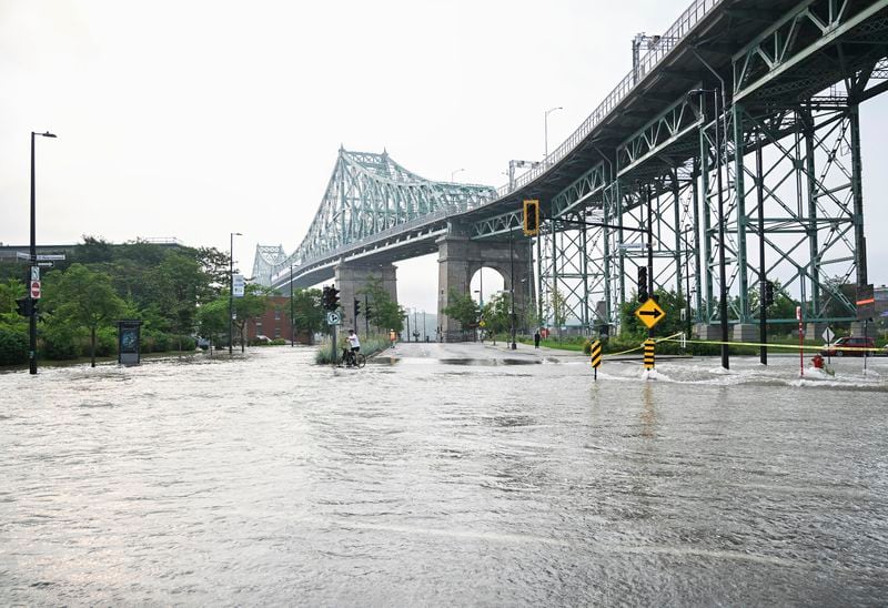 A flooded street is shown due to a broken water main in Montreal, Friday, Aug. 16, 2024, causing flooding in several streets of the area. (Graham Hughes/The Canadian Press via AP)