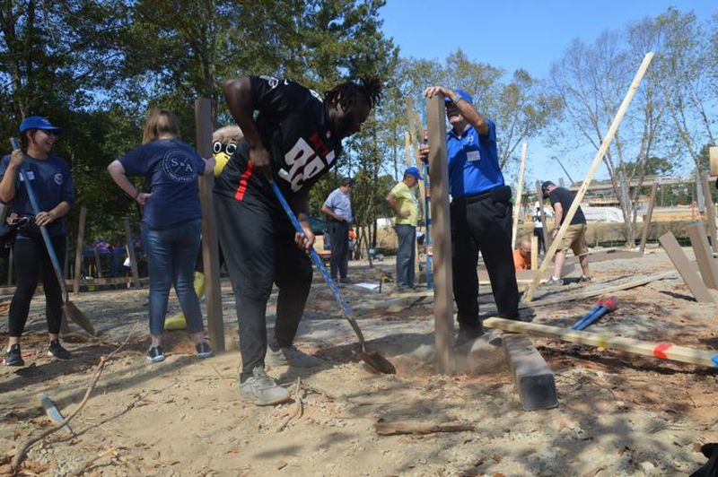 Atlanta Falcons defensive lineman Timmy Horne, center, helps shovel dirt with PlayTown Suwanee volunteers on Tuesday. Members of the Falcons organization volunteered to help build part of the playground at the Suwanee Town Center on Main park site. (Photo Courtesy of Curt Yeomans)