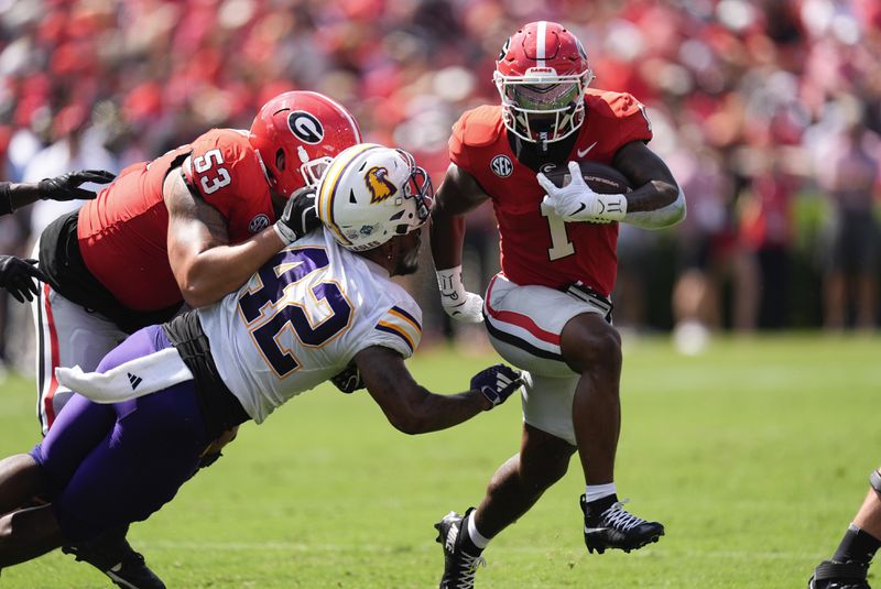 Georgia running back Trevor Etienne (1) breaks through the line of scrimmage as lineman Dylan Fairchild (53) blocks Tennessee Tech linebacker Kalvyn Crummie (42) during the first half of an NCAA college football game Saturday, Sept. 7, 2024, in Athens, ga. (AP Photo/John Bazemore)