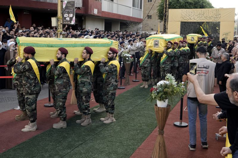 Hezbollah fighters carry the coffins of their comrades who were killed in Friday's Israeli strike, during their funeral procession in the southern suburb of Beirut, Lebanon, Saturday, Sept. 21, 2024. (AP Photo/Bilal Hussein)