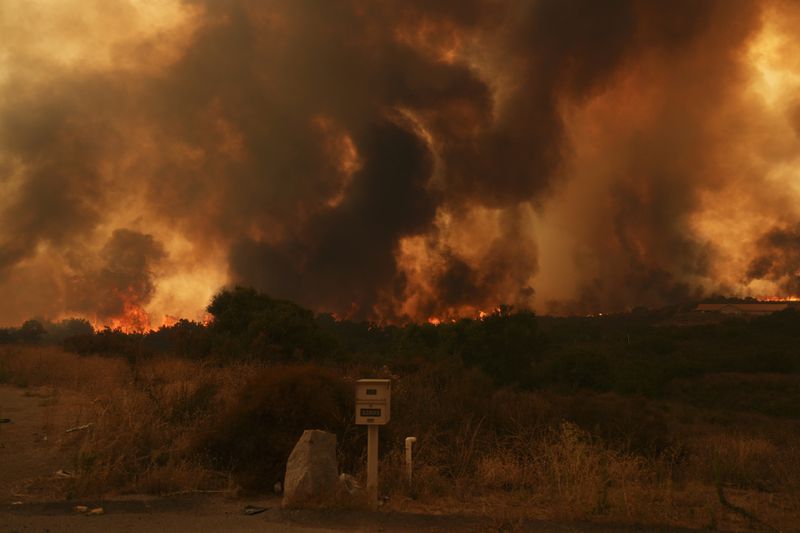 The Airport Fire crests over a mailbox Tuesday, Sept. 10, 2024, in El Cariso, an unincorporated community in Riverside County, Calif. (AP Photo/Eric Thayer)