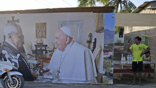 A man stands near a banner showing East Timor's President Jose Ramos-Horta, left, shaking hands with Pope Francis, ahead of the pope's visit to the country, in Dili, Saturday, Sept. 7, 2024. (AP Photo/Dita Alangkara)