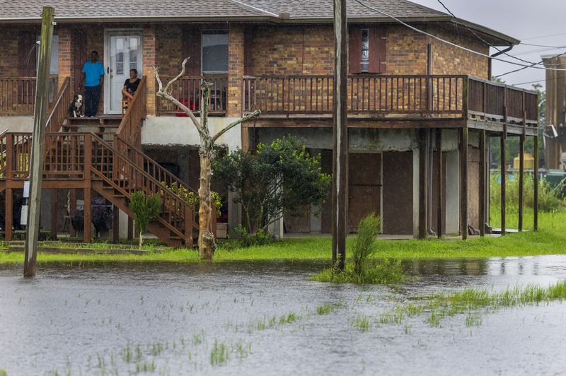 Dulac residents, top left, sit on their front porch as they watch water rise around their elevated home as the effects of Hurricane Francine are felt along the Louisiana coast on Wednesday, Sept. 11, 2024. (Chris Granger/The Times-Picayune/The New Orleans Advocate via AP)