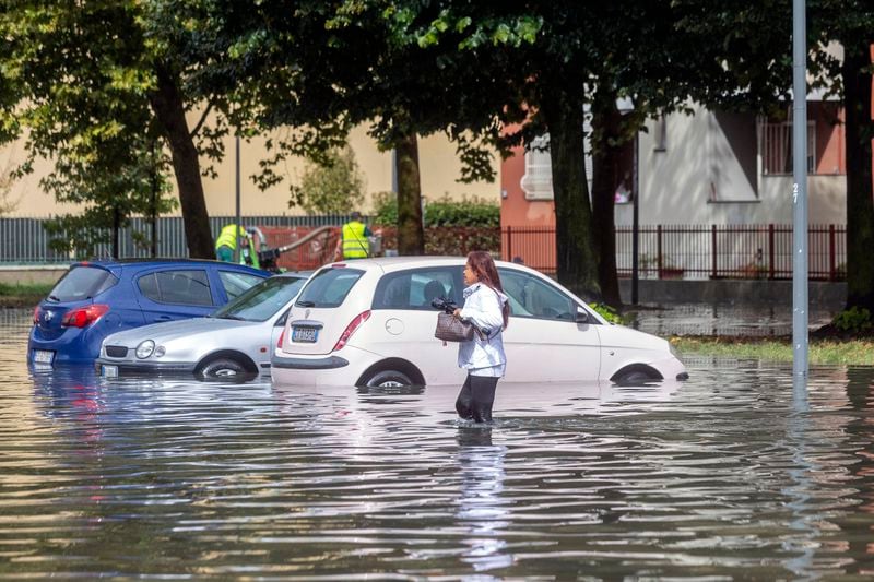 A woman wades through floodwater due to heavy rain in a street in Milan, Italy, Thursday Sept. 5, 2024. (Stefano Porta/LaPresse via AP)