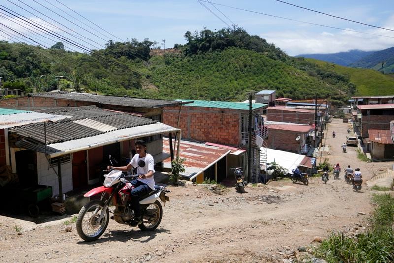 Residents ride their motorcycles on a hilly a dirt road in El Plateado, Colombia, Wednesday, Aug. 14, 2024. The town of 12,000 people lies in the Micay Canyon where rebel groups have entrenched over the past two years despite efforts by Colombian President Gustavo Petro to negotiate peace deals with these irregular armies under a strategy known as total peace. (AP Photo/Fernando Vergara)