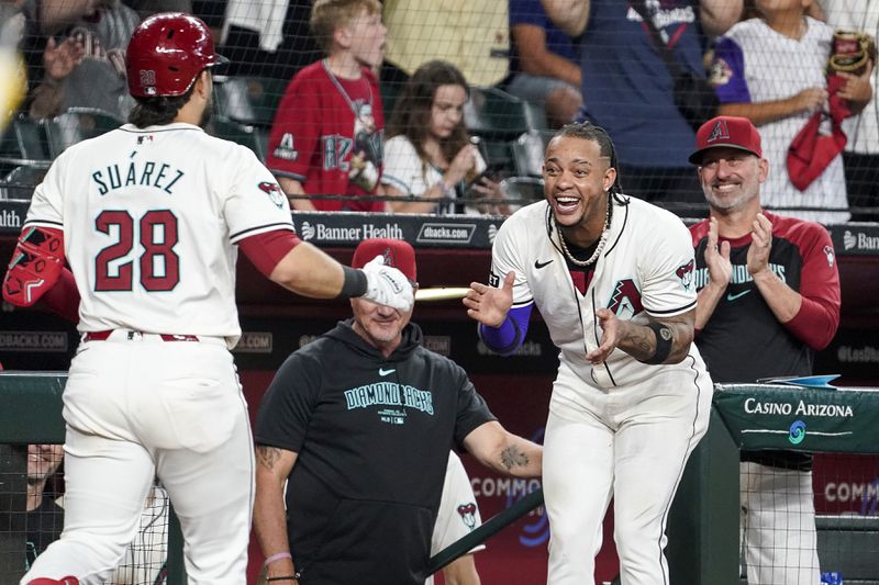 Arizona Diamondbacks' Ketel Marte, right, and manager Torey Lovullo, far right, greets Eugenio Suárez after Suárez's home run against the San Diego Padres during the seventh inning of a baseball game, Sunday, Sept. 29, 2024, in Phoenix. (AP Photo/Darryl Webb)